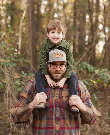 David outdoors with his smiling son sitting on his shoulders